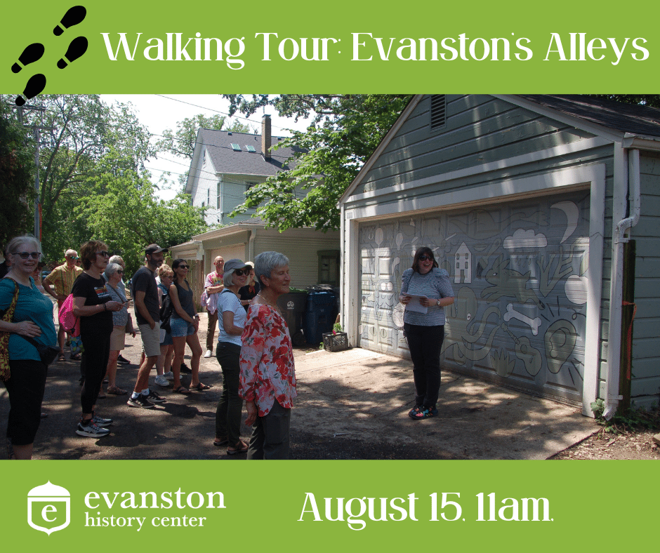 12 people in front of a garage in an alley listening to a woman giving a tour